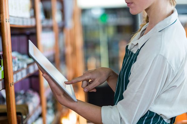 female staff using reading up unlimited user model on digital tablet in supermarket