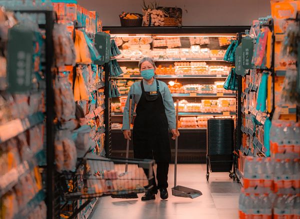 elderly woman carrying dustpans in a grocery store