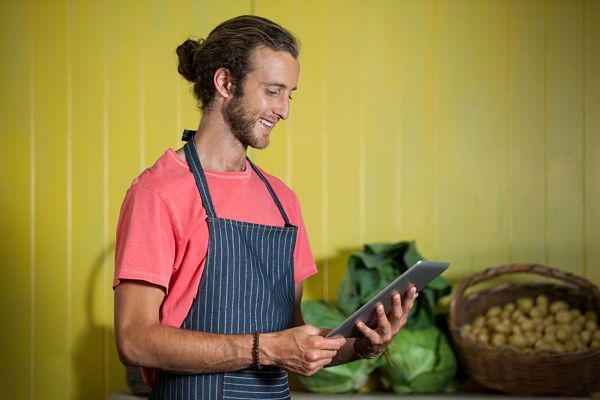 smiling male staff using digital tablet in organic section